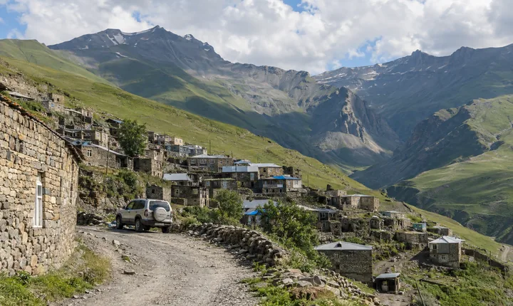 Stone houses of a high Caucasus village above a winding mountain road