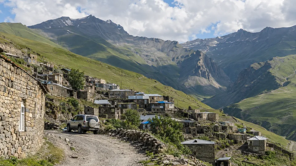 Stone houses of a high Caucasus village above a winding mountain road