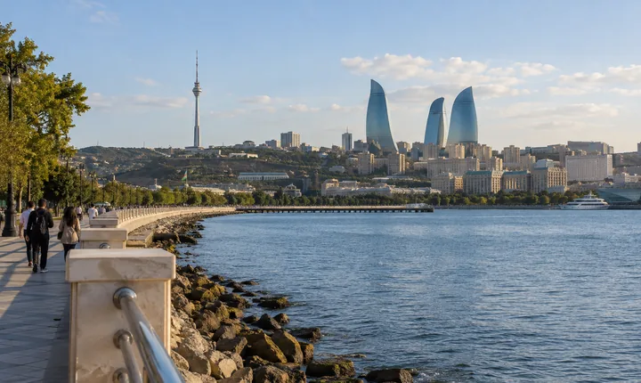 Walkers beside the Caspian waterfront with Baku skyline in the distance
