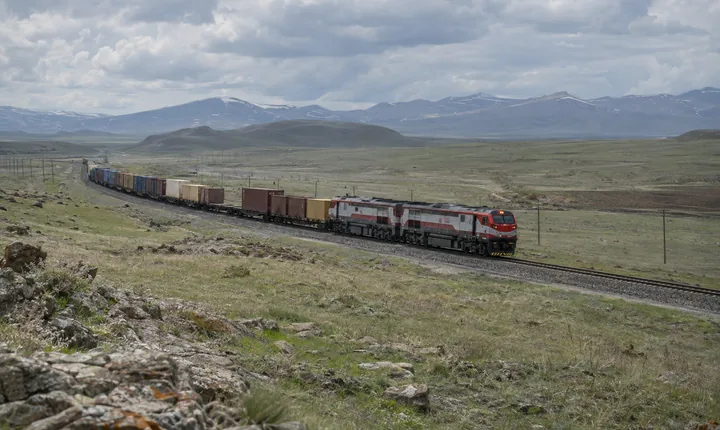 A freight train crossing an open high plateau railway corridor