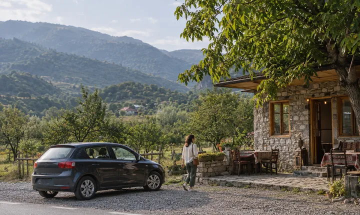 A parked car beside a roadside tea house in wooded Azerbaijani foothills