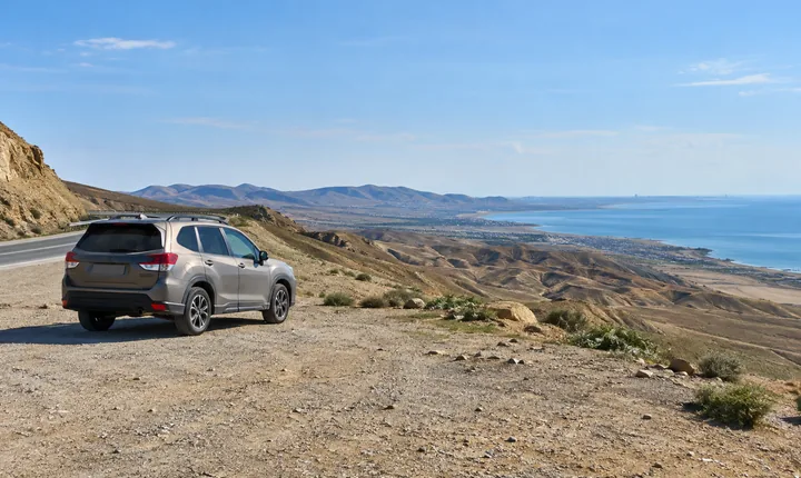 A parked SUV beside an arid coastal road outside Baku