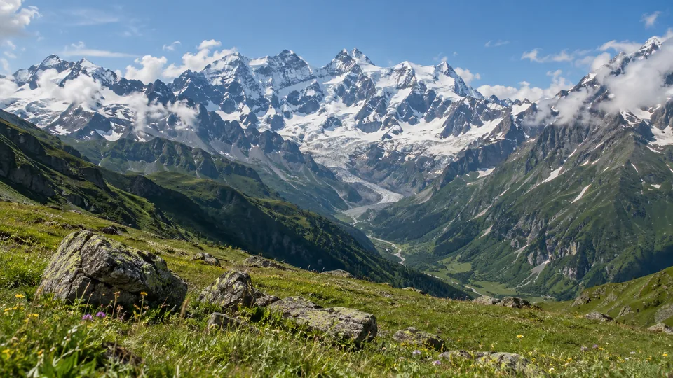 Snow-covered Caucasus peaks and a glacier above a summer alpine meadow