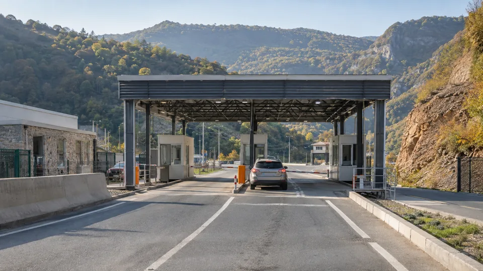 A car approaching a small vehicle border checkpoint in the wooded South Caucasus