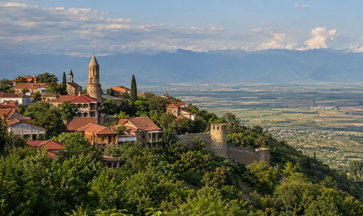 Red-roofed Georgian hilltown houses and stone walls overlooking a wide green valley