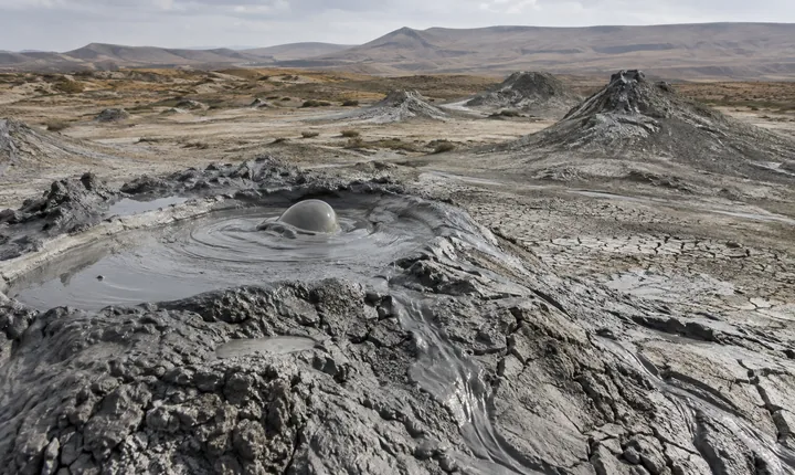 A small bubbling mud vent and low cones in an arid Gobustan landscape