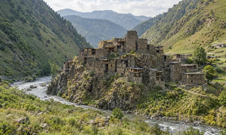 Stone towers of Shatili fortress village beside a river in the green Caucasus mountains