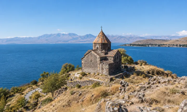 Sevanavank monastery above the blue water of Lake Sevan and its surrounding mountain rim