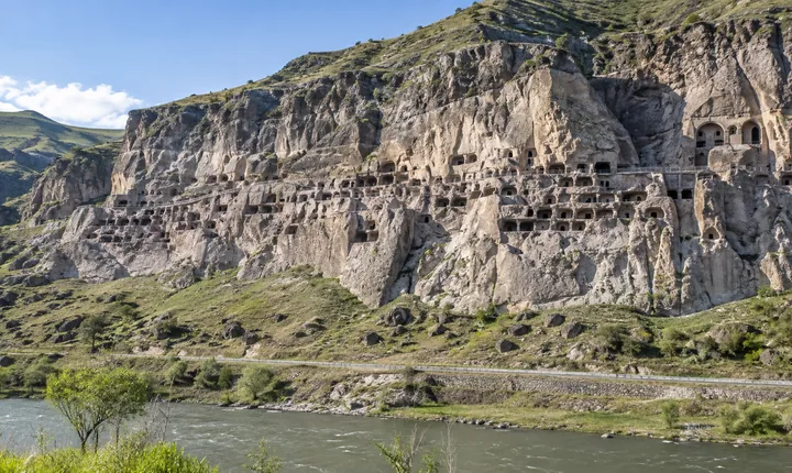 The cave openings of Vardzia stretch across a volcanic cliff above the Mtkvari valley