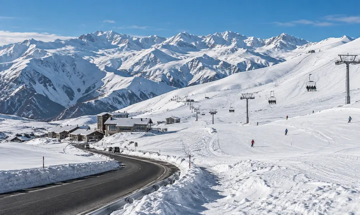 Ski slopes, chairlift and a plowed access road at Gudauri beneath snowy Caucasus ridges