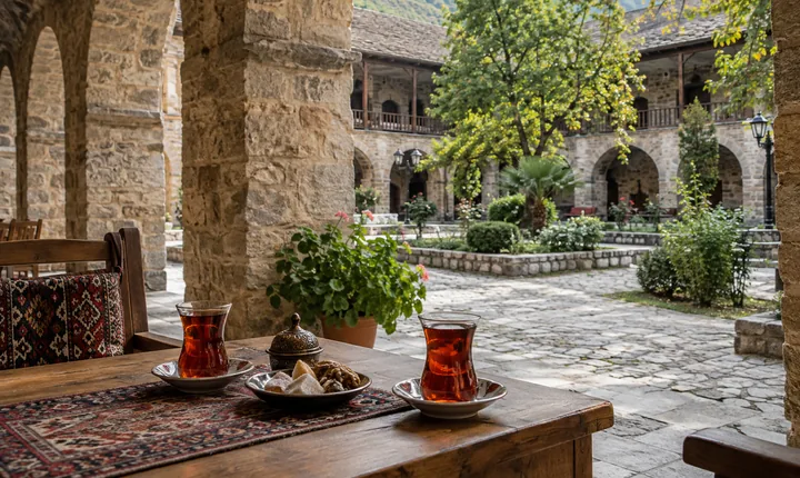Tea glasses and sweets beside stone arches in a Sheki courtyard