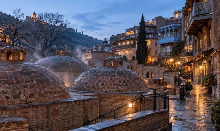 Brick sulfur-bath domes and warm old-town windows in Tbilisi at winter twilight