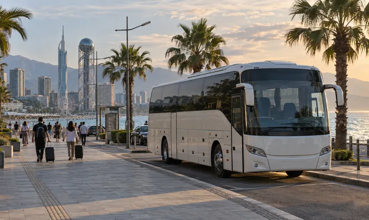 An intercity coach at a coastal curbside bay with palm trees and the Black Sea beyond