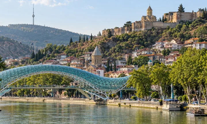 The curved glass Peace Bridge spans the Mtkvari River beside Tbilisi's Old Town