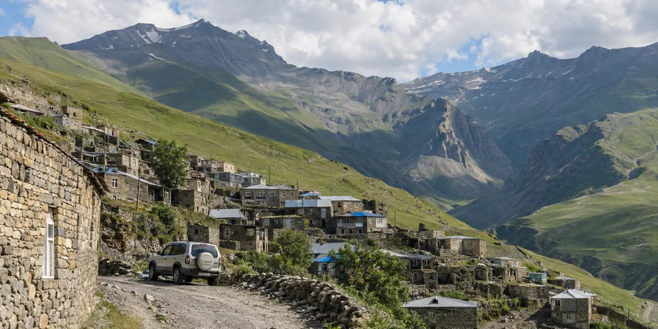 Каменные дома высокогорной деревни Caucasus над извилистой горной дорогой