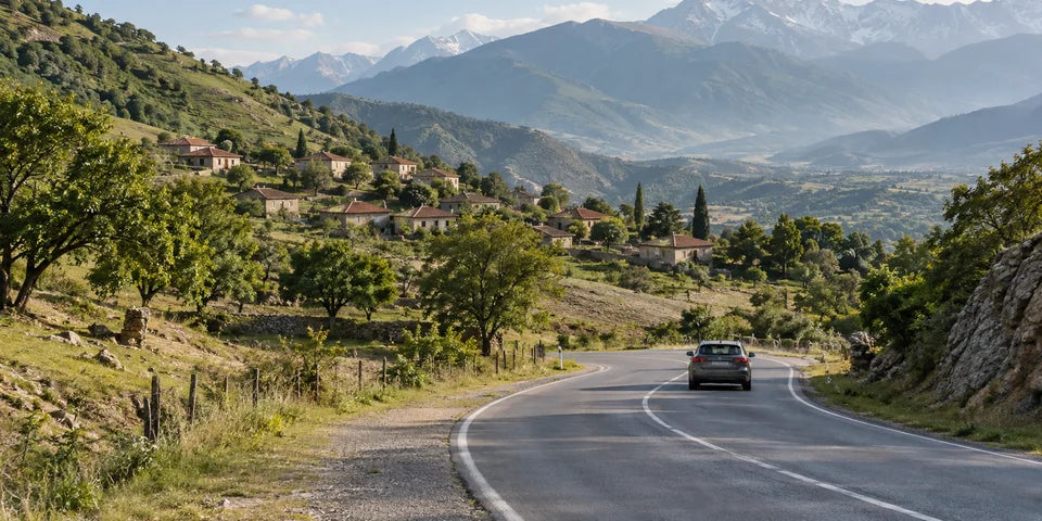Eine befestigte Straße windet sich durch das Caucasus-Vorgebirge an Dorfhäusern und Walnussbäumen vorbei