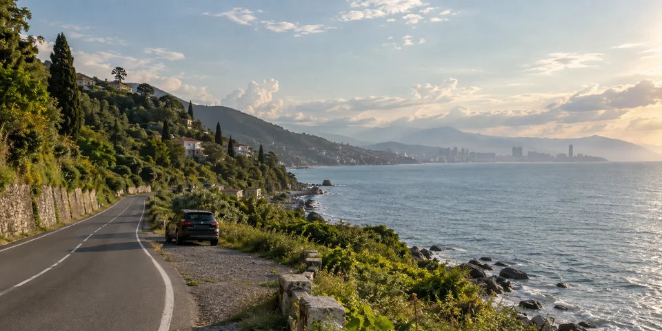 Un SUV garé près d’une route côtière avec la mer Noire géorgienne et des contreforts verdoyants au-delà