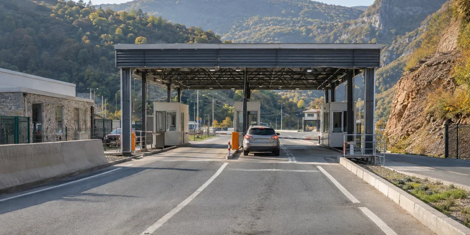 Ein Auto nähert sich einem kleinen Fahrzeuggrenzkontrollpunkt im bewaldeten Südcaucasus
