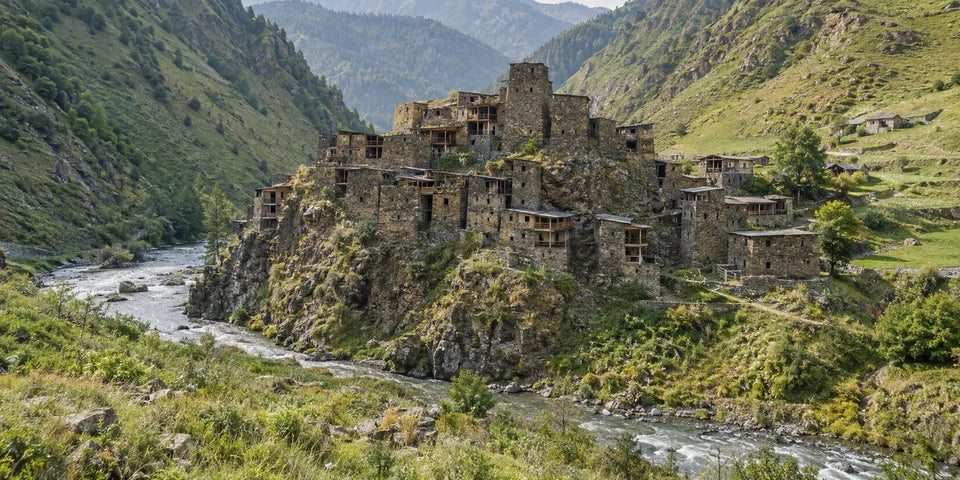 Steintürme des Festungsdorfs Shatili neben einem Fluss in den grünen Caucasus-Bergen