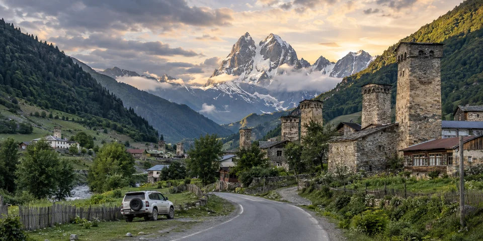 Eine befestigte Straße führt zu den Steintürmen von Mestia unter den Gipfeln von Svaneti