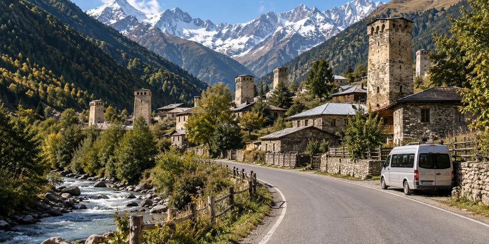Approach road to Mestia with stone Svan towers, a small passenger minibus and forested Caucasus mountains