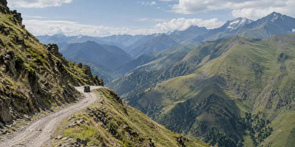 Schotterstraße über den Abano Pass in Richtung Tusheti mit einem kleinen 4x4 und grünen Caucasus-Hängen