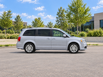 Иллюстративное изображение, созданное ИИ: Dodge Grand Caravan 2018, вид сбоку на сухом дорожном покрытии в городской обстановке. Цвет и комплектация реального автомобиля могут отличаться.