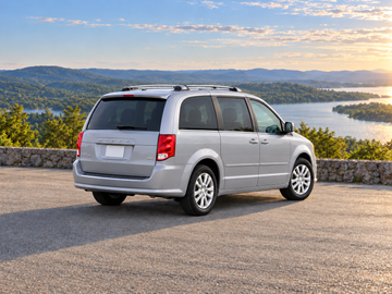 Иллюстративное изображение, созданное ИИ: Dodge Grand Caravan 2018, вид сзади в три четверти на сухом дорожном покрытии среди живописного пейзажа. Цвет и комплектация реального автомобиля могут отличаться.
