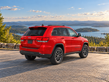 Иллюстративное изображение, созданное ИИ: Jeep Grand Cherokee 2017, вид сзади в три четверти на сухом дорожном покрытии среди живописного пейзажа. Цвет и комплектация реального автомобиля могут отличаться.