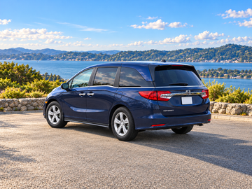 Иллюстративное изображение, созданное ИИ: Honda Odyssey 2018, вид сзади в три четверти со стороны водителя на сухом дорожном покрытии среди живописного пейзажа. Цвет и комплектация реального автомобиля могут отличаться.